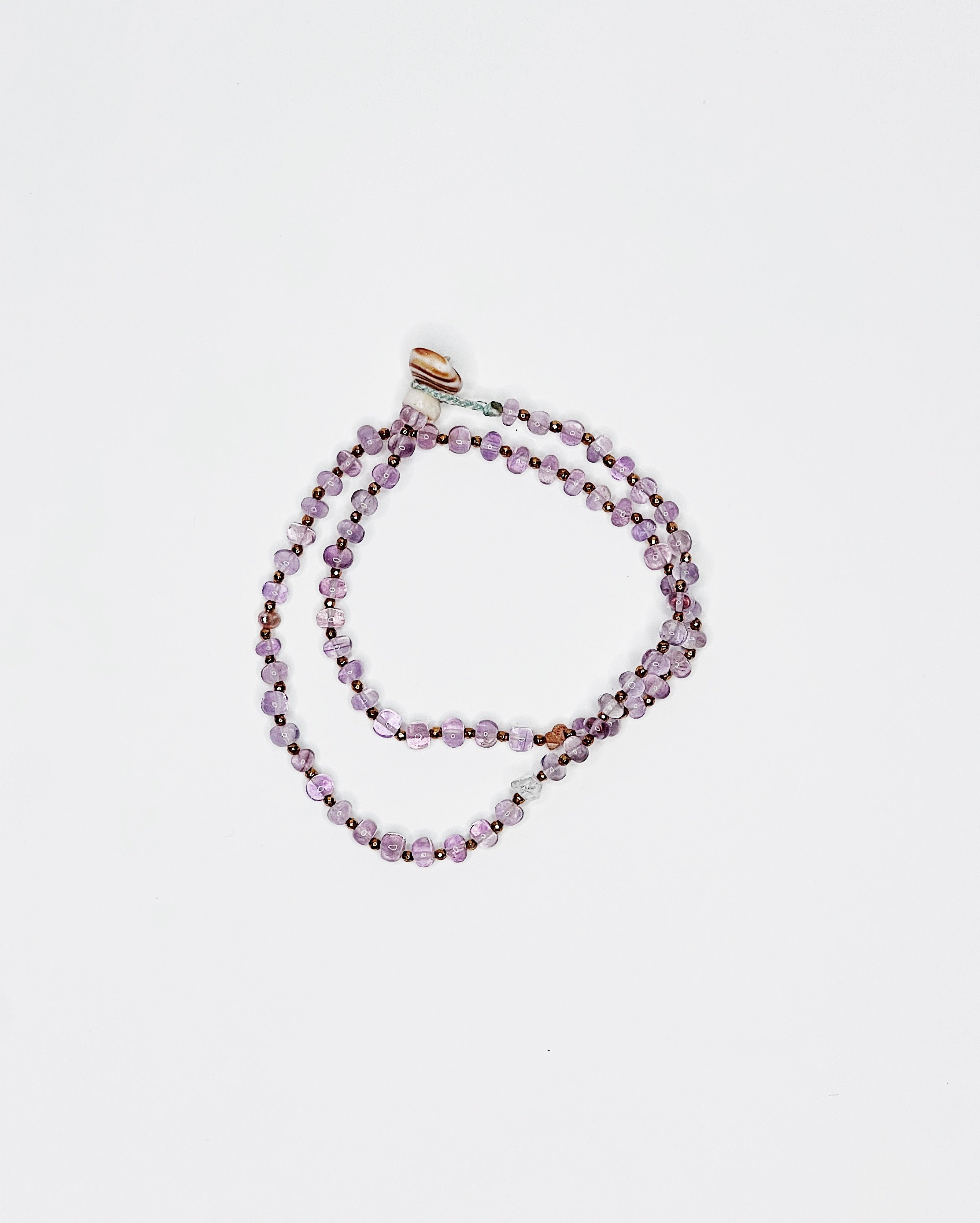 Handmade amethyst choker with gold spacers, Kahelelani shell and tourmaline accents, finished with puka shell clasp. White background