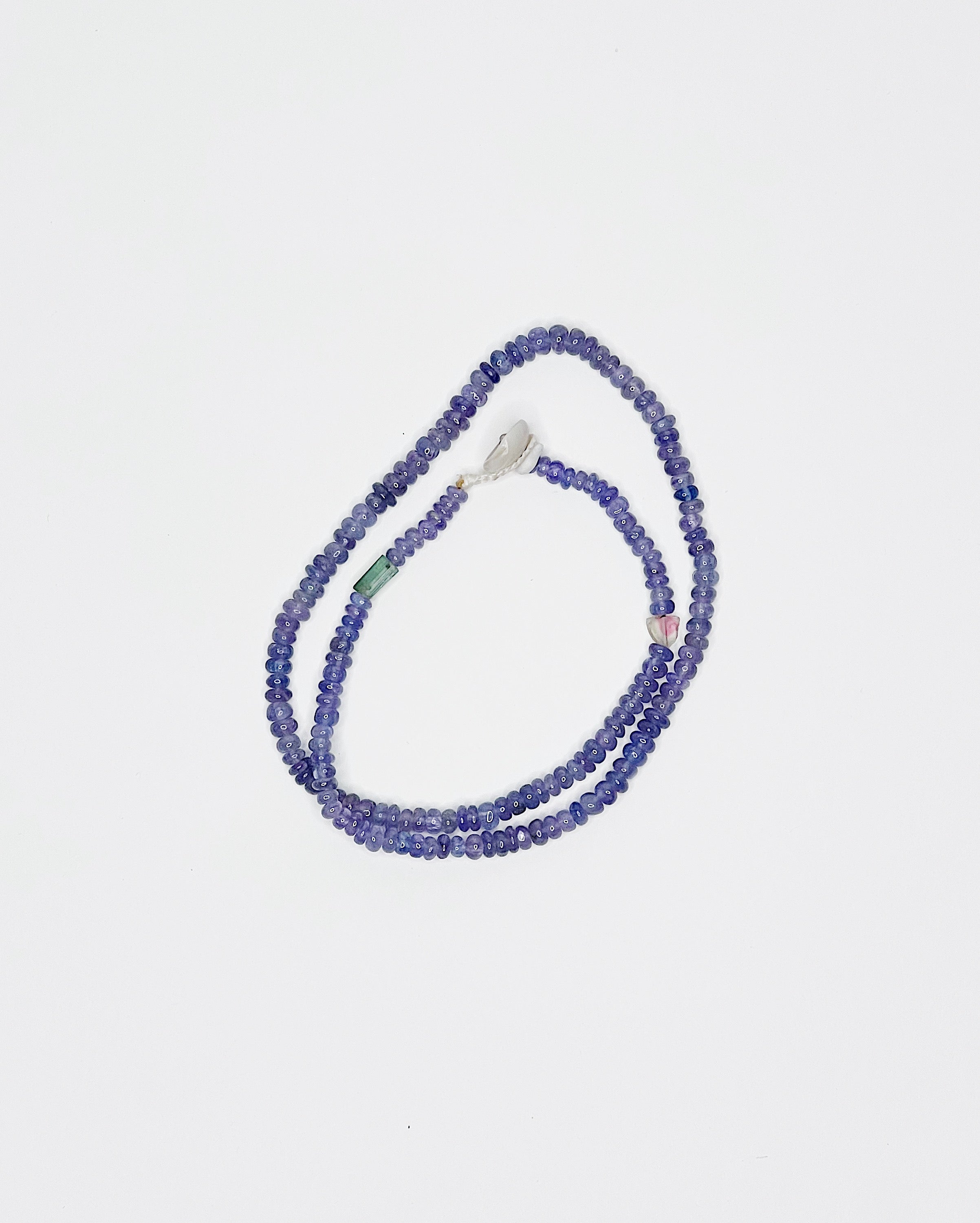 Handmade tanzanite choker with tourmaline accents, finished with puka shell clasp. White background