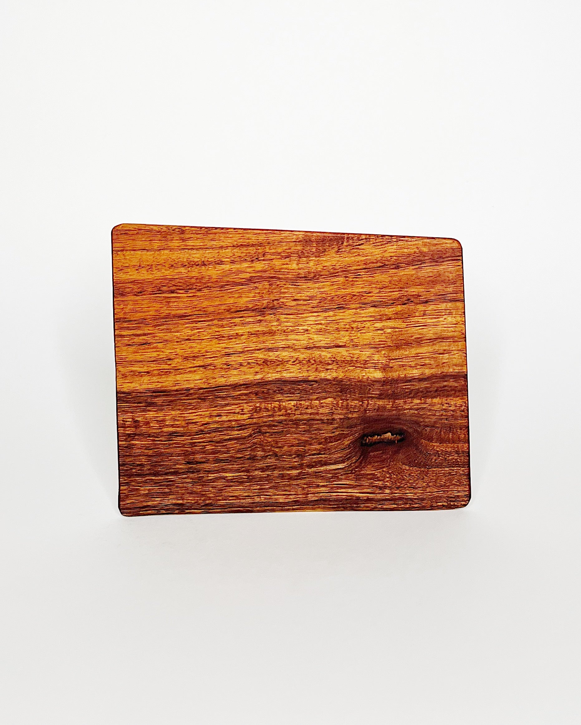 Handmade rectangular Hawaiian hardwood cutting board with rich golden and reddish wood grain, featuring a natural knot detail, displayed against a white background