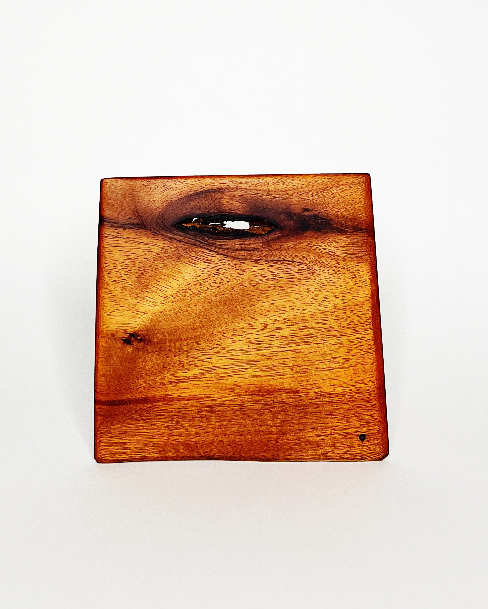 Handmade Hawaiian hardwood cutting board with warm golden tones, featuring a dramatic natural knot and swirling grain pattern, displayed against a white background