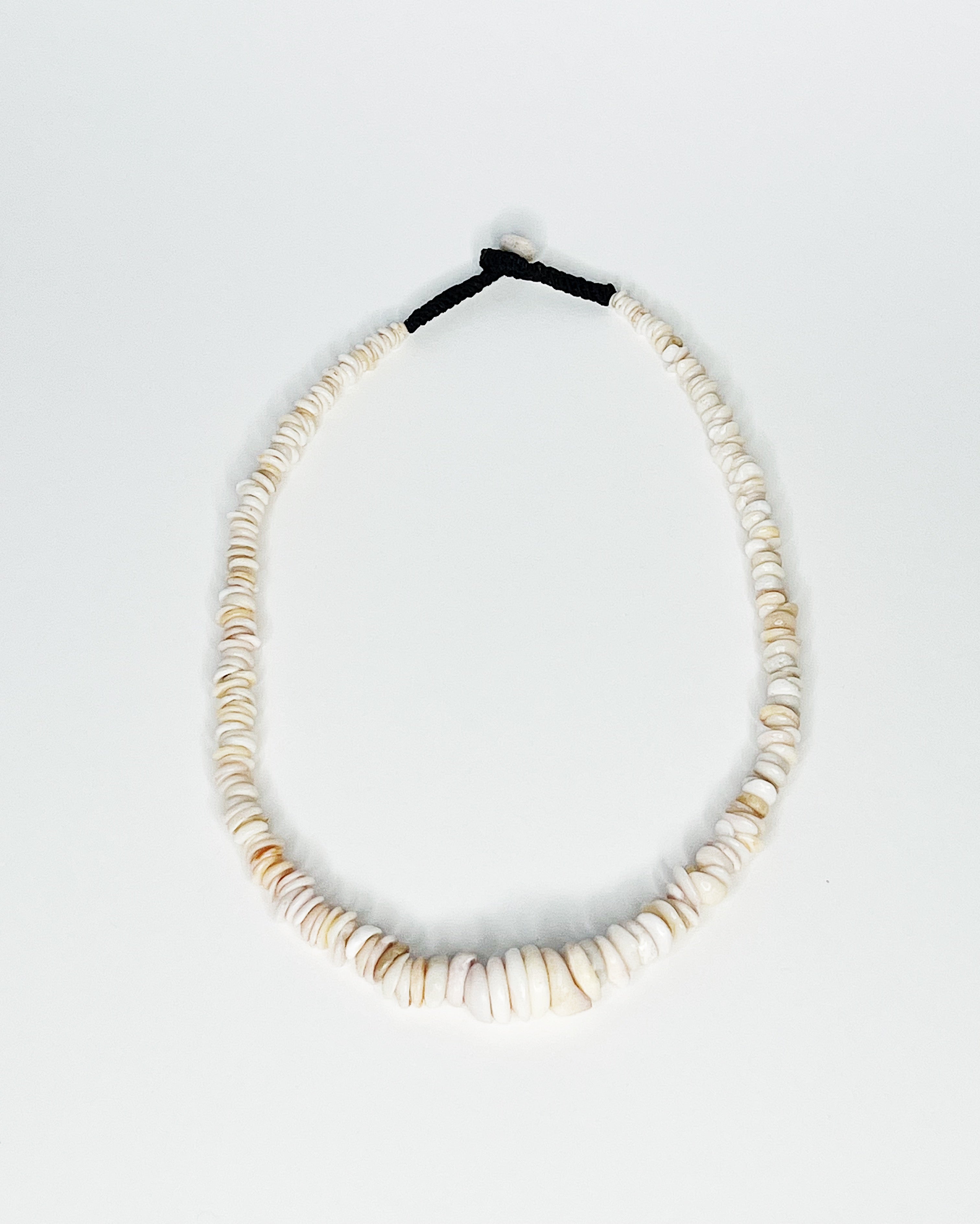 Expertly handcrafted puka shell necklace featuring naturally polished white and tan kauai puka shells strung on a durable black cord with a puka shell button clasp, displayed against a white background
