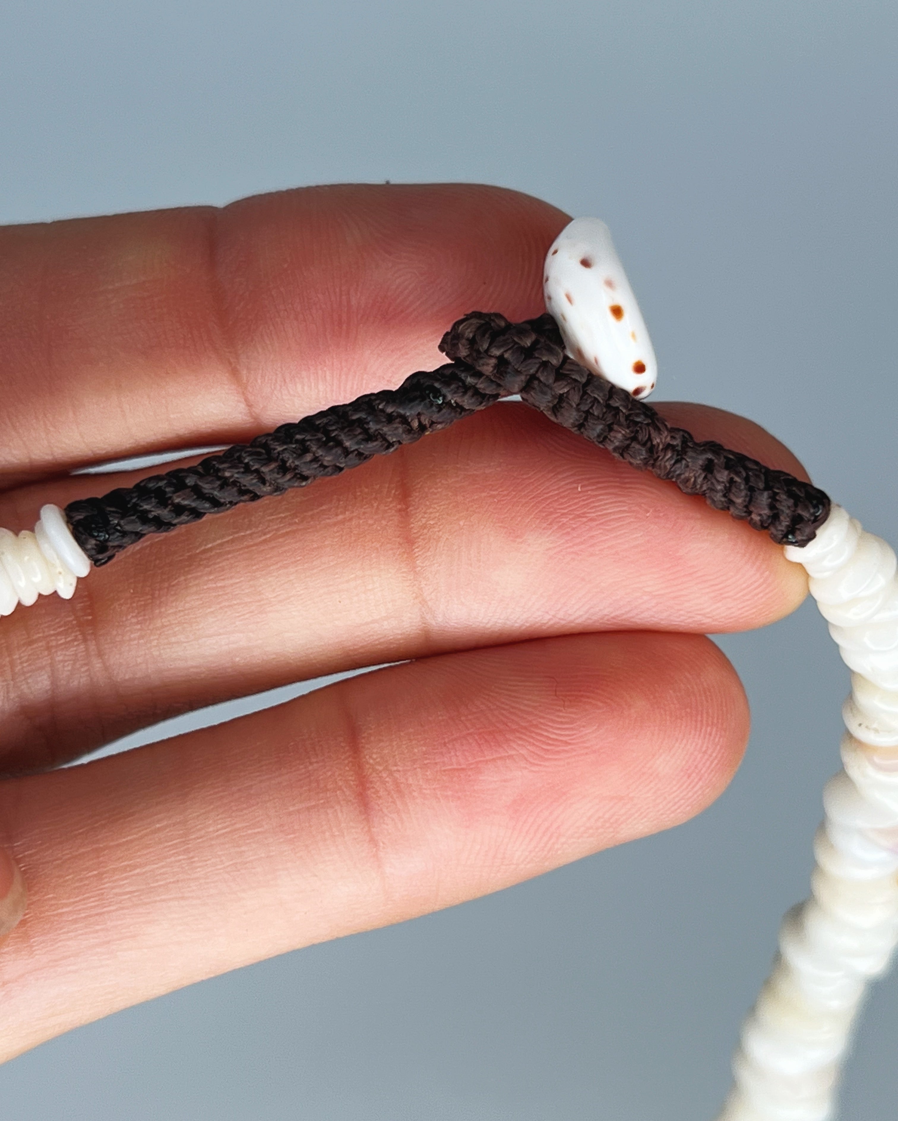 Close up of hand showing puka shell clasp