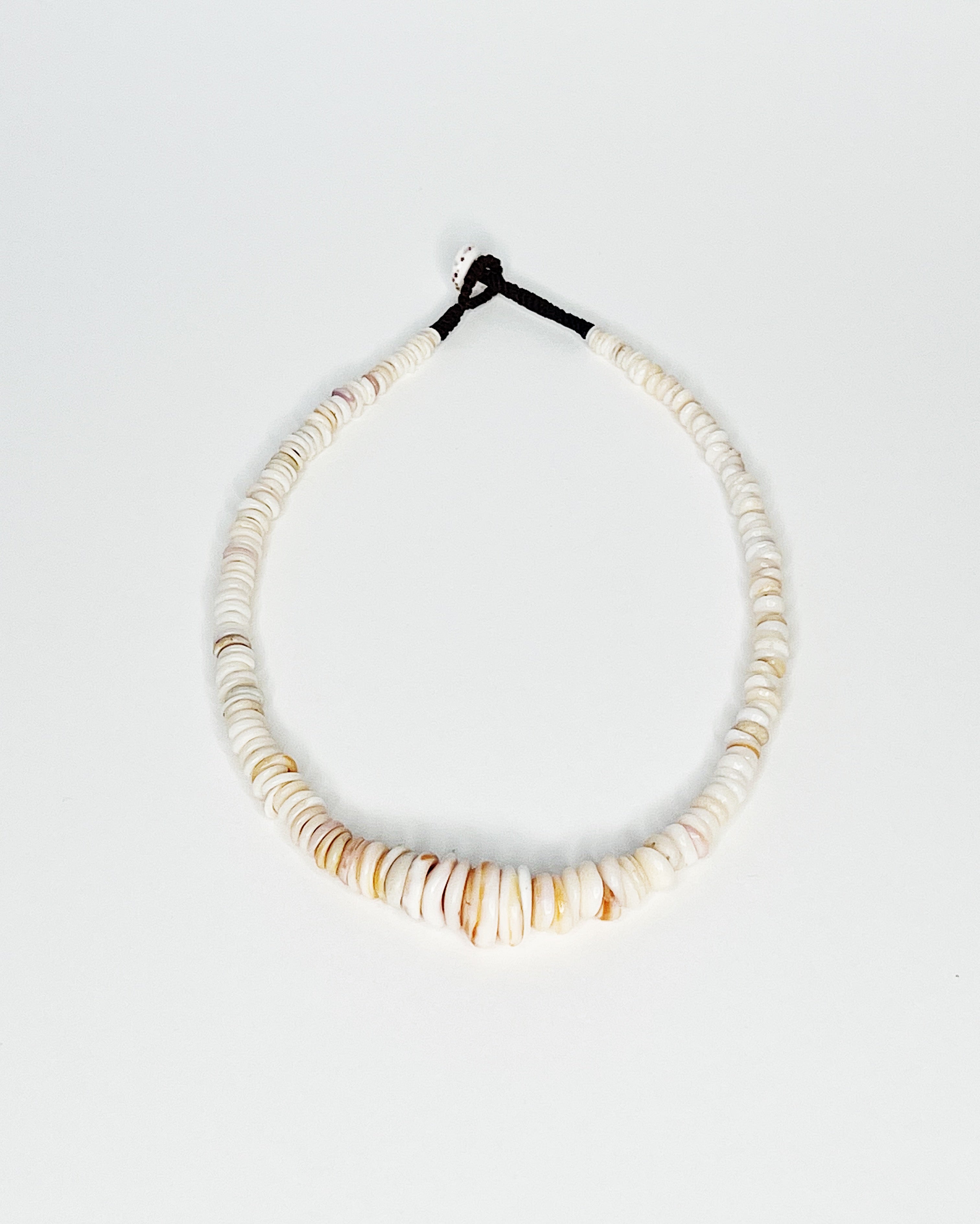 Expertly handcrafted puka shell necklace featuring naturally polished white and tan kauai puka shells strung on a durable black cord with a puka shell button clasp, displayed against a white background