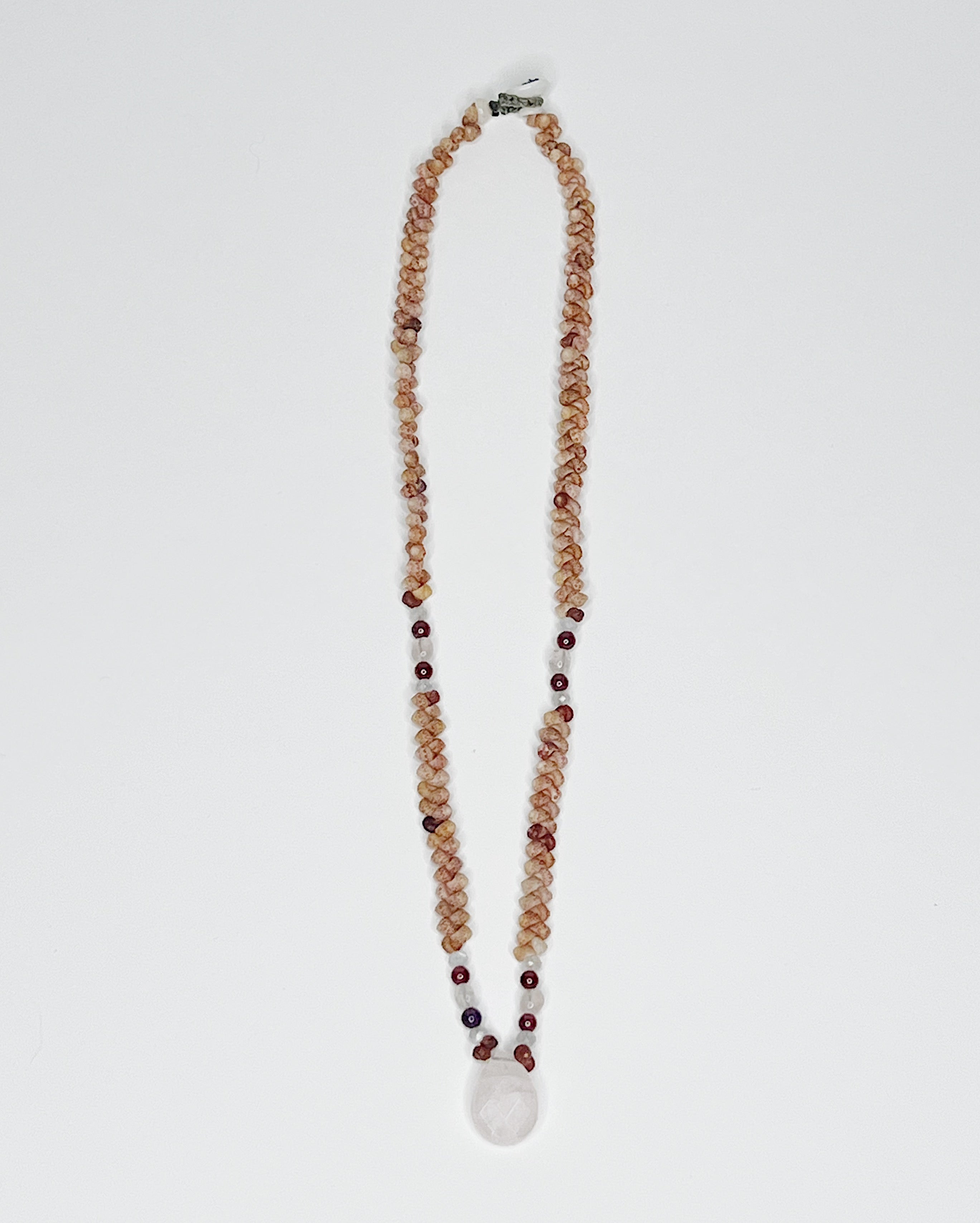 Handmade necklace featuring natural Kauaʻi Kahelelani shells intricately woven together, accented with garnet and moonstone beads and a faceted rose quartz teardrop pendant at the center, displayed against a white background