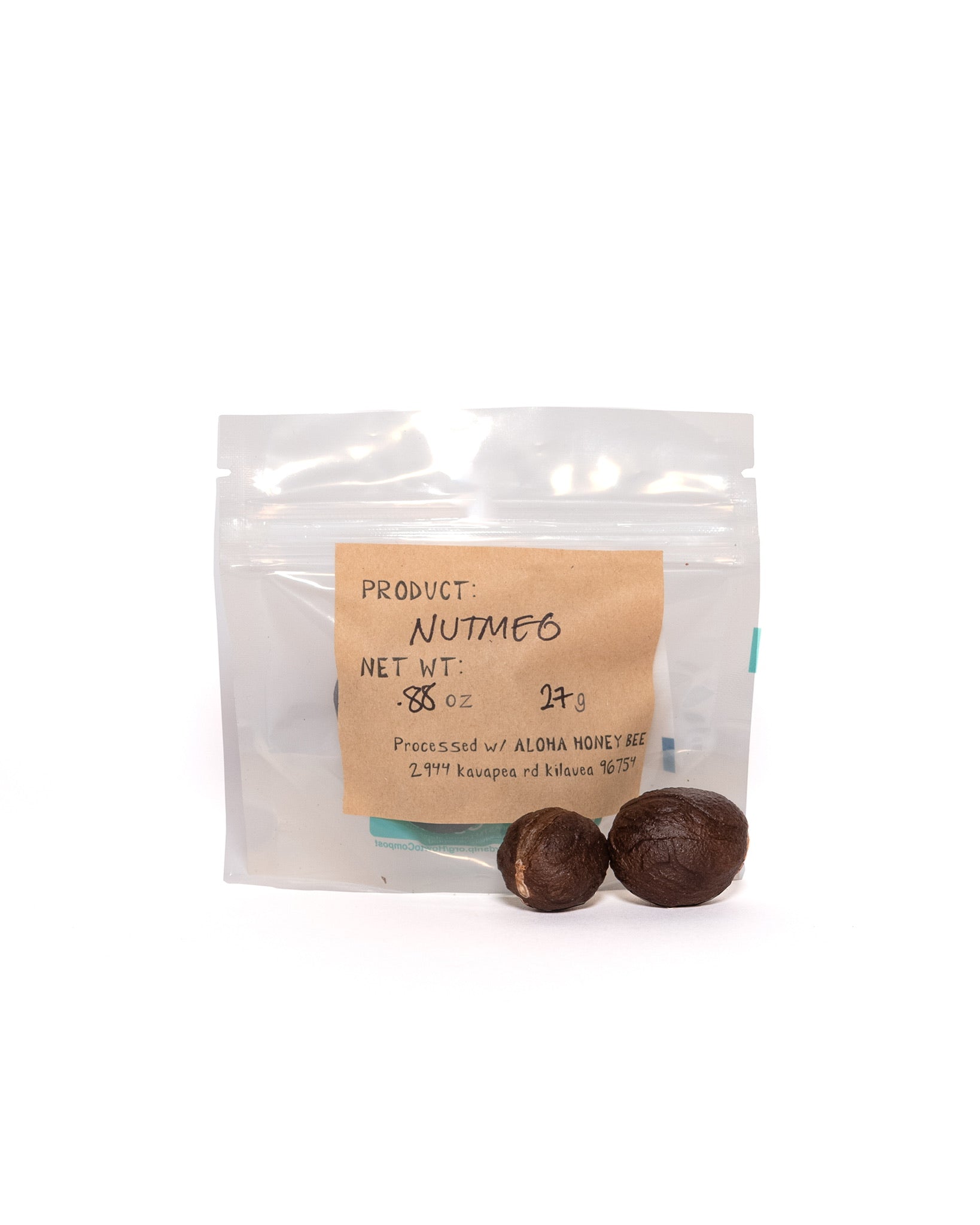 Clear pouch of organic nutmeg with handwritten kraft paper label showing weight and processing info with two round nutmeg seeds outside the package.