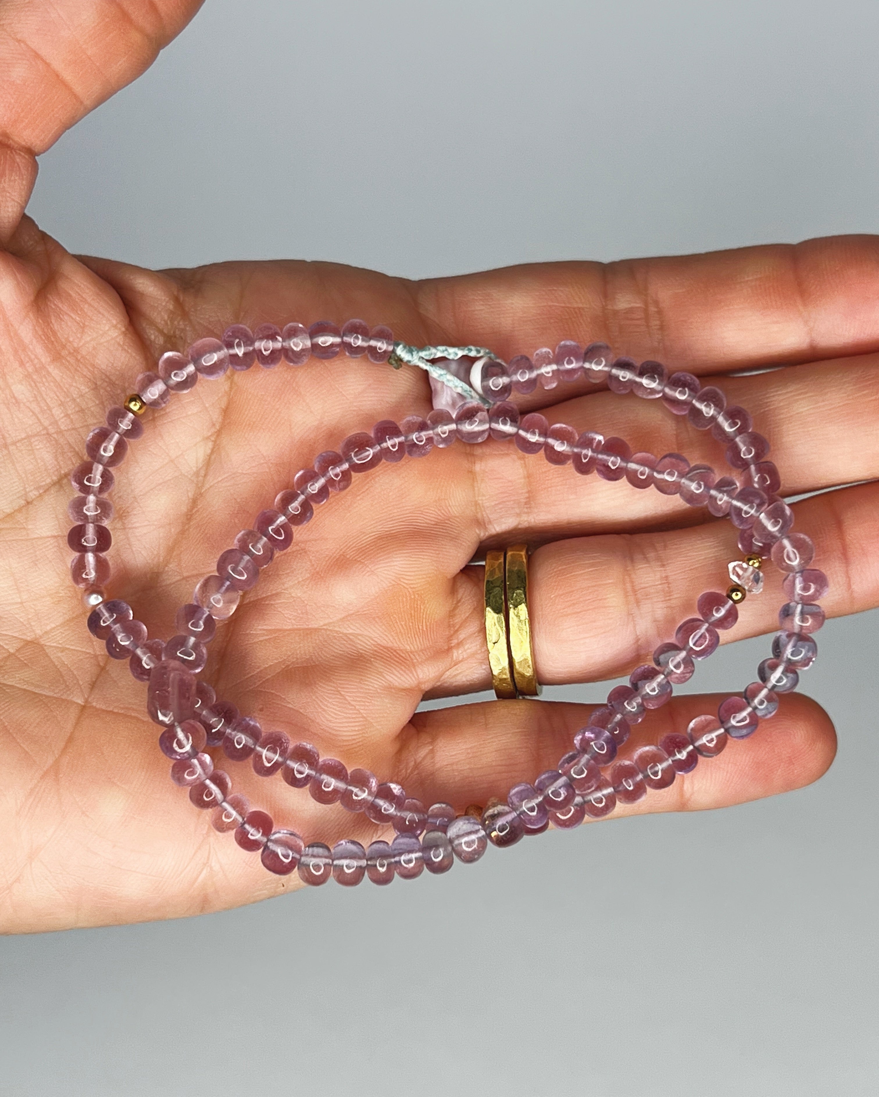 Handmade amethyst choker with Kahelelani shell and tourmaline accents, finished with puka shell clasp. White background 
