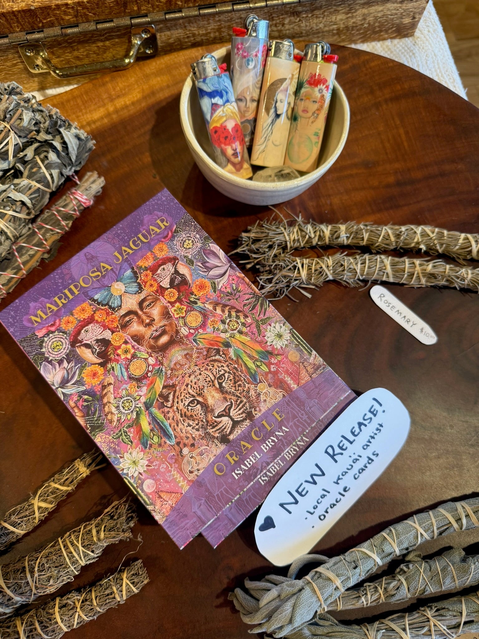 Colorful book titled 'Mariposa Jaguar' with smudge sticks and a bowl of incense on a wooden surface.
