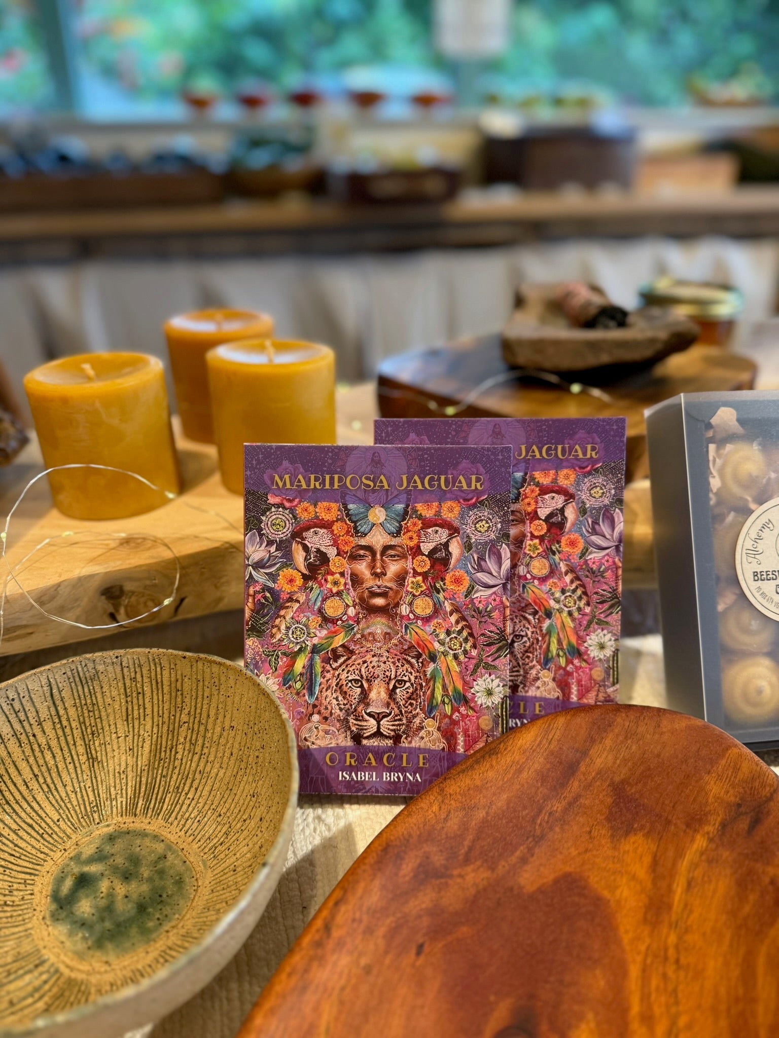 Colorful tarot cards on a wooden surface with candles and a bowl in the background.