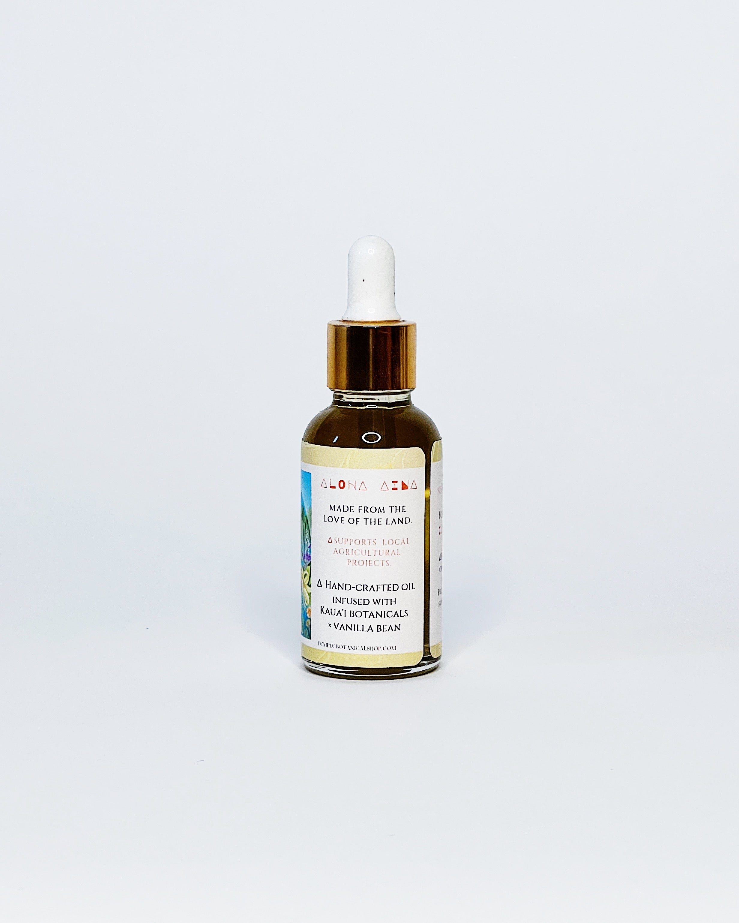 Side view of Temple Kukui Nut Oil bottle showing a label describing the product as hand-crafted from Kauaʻi botanicals and vanilla bean, supporting local agricultural projects